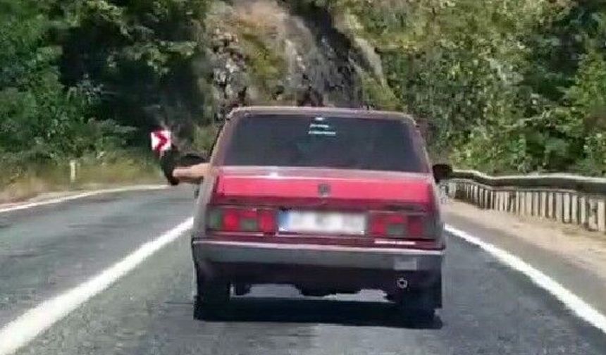 Ayaklarını camdan sarkıtarak trafiği tehlikeye attı